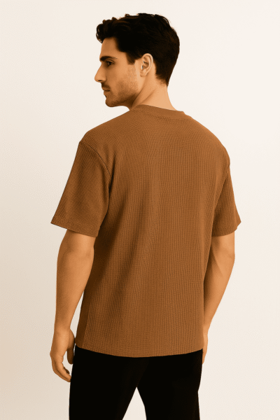 Man wearing a brown ribbed t-shirt on a beige background