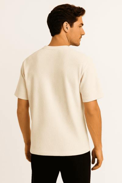 Man wearing a beige ribbed t-shirt on a plain background